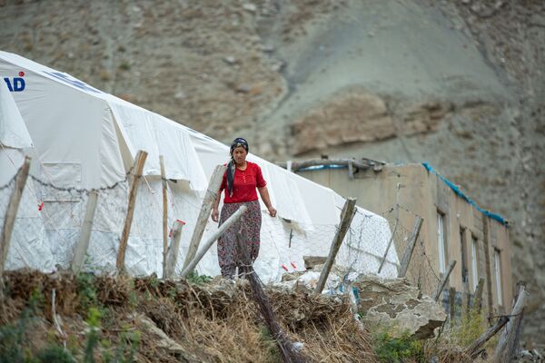 Kadınlar bir taraftan sağlam kalan eşyalarını kurtarmaya çalışırken bir taraftan da çadırda günlük işlerini yapmaya çalışıyor. - Sputnik Türkiye