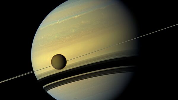 Saturn's largest moon Titan passing in front of the giant planet in an image made by NASA's Cassini spacecraft - Sputnik Türkiye