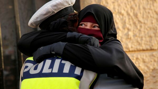Danimarka'da yürürlüğe giren peçe yasağını protesto eden Ayah adlı eylemciye sarılan kadın polis - Sputnik Türkiye