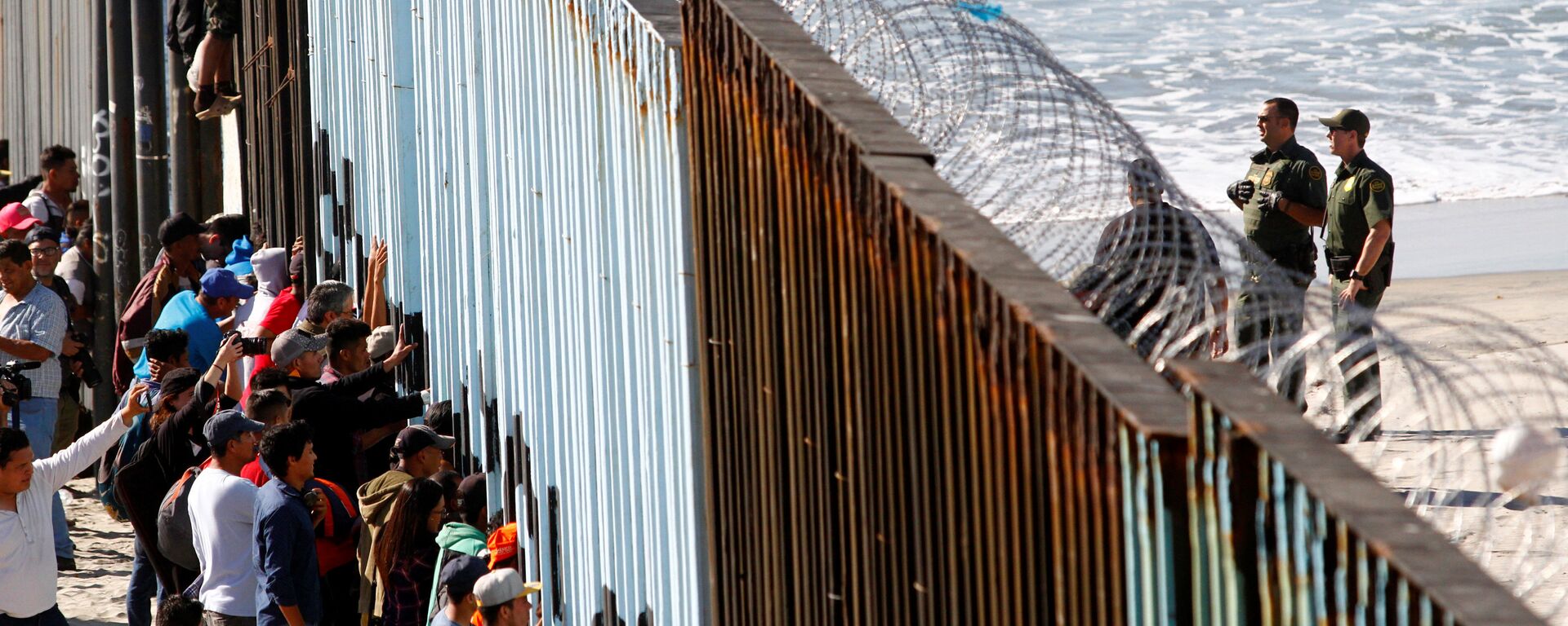 Orta Amerikalı göçmen kervanından 800-1000 kişilik bir grup, Meksika'nın ABD sınırındaki Tijuana'ya ulaştı. Göçmenler, kentte ABD ile sınırı belirleyen duvarı adeta kuşatmaya aldı. - Sputnik Türkiye, 1920, 15.03.2022