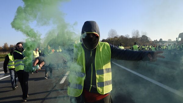 A man holds a flare as demonstrators wearing yellow vests (Gilets jaunes) protest against the rising of the fuel and oil prices on November 17, 2018 in Haulchien near Valenciennes, northern France. - Sputnik Türkiye