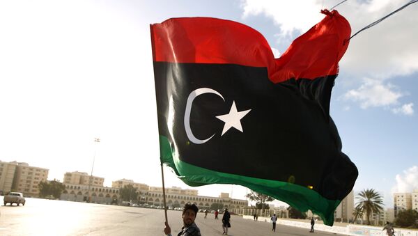 A Libyan man waves a national flag - Sputnik Türkiye