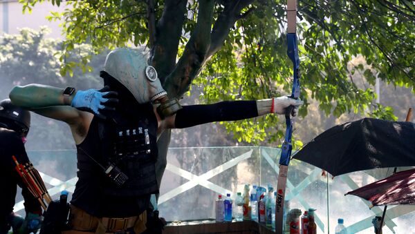 Hong Kong Polytechnic Üniversitesi'nde (PolyU) işgal eylemi düzenleyenlerden biri polisle çatışmalarda ok atarken - Sputnik Türkiye