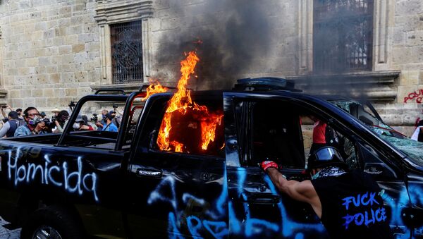 Meksika'da bir kişinin polis şiddetiyle öldürüldüğü iddiasıyla başlayan protestolarda göstericiler, bir polisi ateşe verdi. - Sputnik Türkiye